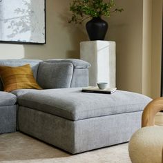 a living room with a couch, chair and vase on the floor in front of it