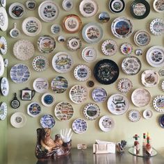 many plates are arranged on the wall above a table