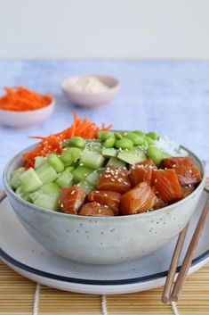 a bowl filled with carrots, celery and meat next to chopsticks