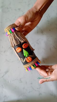 two hands are holding something made out of beads and other things that are on top of each other