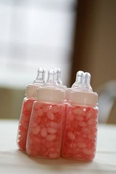 two baby bottles filled with pink candy on top of a table