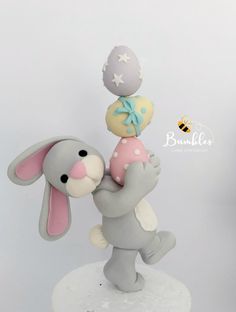 a cake topper with an elephant and bunny on it's back holding a ball