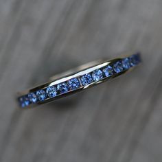 a gold ring with blue sapphires on it sitting on a wooden surface in front of a brick wall