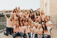 a group of young women sitting next to each other in front of a brick building