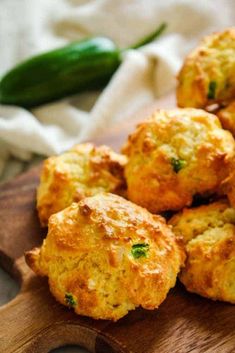 some fried food on a wooden cutting board next to a green pepper and jalapeno