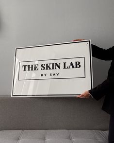 a man in a suit holding up a sign that says the skin lab by sav