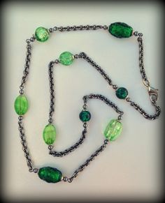 This necklace features an array of green glass beads alongside antique silver-finish cable chain. It's accented with smooth round antique silver-finish beads and bead caps.  It's finished with a lobster clasp closure. Please convo with any questions! Length-23"-24 3/4" ~Hand Crafted           & Custom Made~ Green Necklaces With Round Beads Chain, Green Round Beaded Nickel-free Necklace, Green Nickel-free Round Beaded Necklace, Green Beaded Chain Necklace Gift, Green Beaded Necklace With Chain For Gift, Green Antique, Station Necklace, Bead Caps, Cable Chain