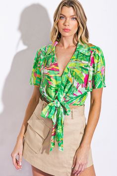 A printed woven top featuring shirt collar, V neckline, flutter sleeve and front tie. Matching pant IP8428Details:Self : 100% PolyesterSize & Fit- Model is 5`8" And Wearing Size Small- Measurements Taken From Size Small- Approx. Length: 16" Green Printed Blouse For Day Out, Printed Green Blouse For Day Out, Spring Green Blouse With Collared Neckline, Chic Green Blouse For Vacation, Green Rayon Summer Blouse, Green Rayon Blouse For Summer, Green Tie Neck Top For Summer, Summer Printed Tie Neck Tops, Summer V-neck Blouse With Tie Waist