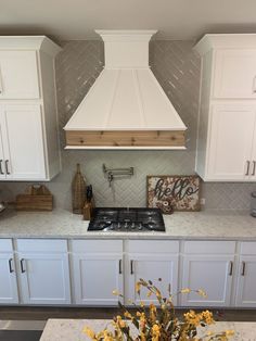 a kitchen with white cabinets and yellow flowers on the counter top in front of an oven