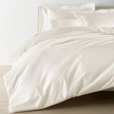 an unmade bed with white sheets and pillows