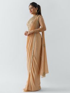 A two-piece peach saree set from the Suruchi Parakh collection. This beautiful pre drape saree is paired with a hand-crafted blouse. The pallu of the pre draped saree has hanging tassels to it. The peach color touch enhances the graceful georgette crepe pre drape saree. The peach blouse has a crew neckline along with geometrical & floral handwork detail. Formal Anarkali Chanderi Pre-draped Saree, Anarkali Style Chanderi Pre-draped Saree For Formal Occasions, Traditional Peach Pre-draped Saree With Zari Work, Traditional Peach Pre-draped Saree For Festive Occasions, Orange Pre-draped Saree For Diwali, Formal Pre-draped Saree For Navratri, Traditional Drape Tissue Silk Pre-draped Saree For Reception, Peach Semi-stitched Saree For Navratri, Traditional Peach Pre-draped Saree With Dupatta