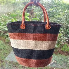 a brown, black and white striped bag hanging from a window sill with trees in the background