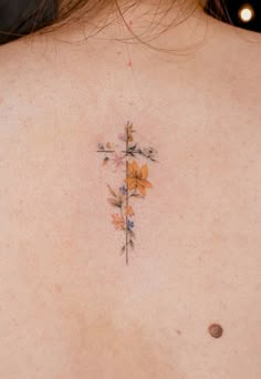 a cross tattoo on the back of a woman's shoulder