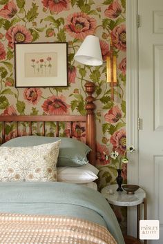 a bed sitting in a bedroom next to a wallpaper covered with pink and green flowers