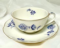 a blue and white china tea cup and saucer set on a white tablecloth