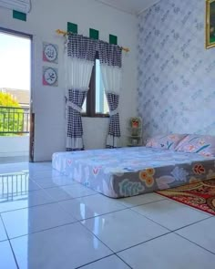 a bed sitting in the middle of a room next to a window with curtains on it