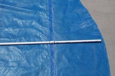 a blue tarp with a white stick sticking out of it's end on the ground