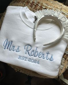 a white shirt with the name mrs roberts on it and a hair clip in front of it