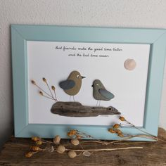 two birds sitting on top of a piece of driftwood in front of a blue frame