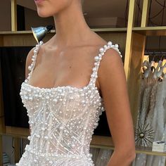 a woman in a white dress standing next to a shelf