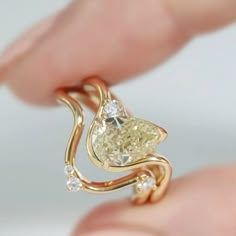 a woman's hand holding a yellow diamond ring