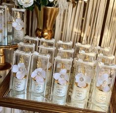 the bottles have flowers in them and are lined up on a table with gold trimmings