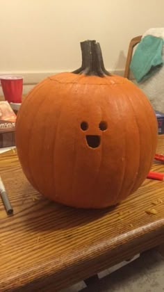 a pumpkin sitting on top of a wooden table next to a marker and pencils