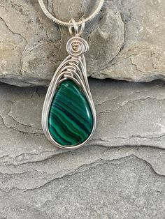 This Malachite necklace is simple yet elegant.  Malachite is a beautiful green color with unique striping/bands of color. I chose to enhance this beautiful smoothstone with a Celtic inspired silver wire design to let the natural beauty of the gemstone shine. This necklace is handmade by me with a synthetic malachite stone The necklace you will receive will be similar to the one in the picture, each stone is unique. The 4th photo in my listing shows the subtle variations of these Beautiful genuin Handmade Green Malachite Necklaces, Green Malachite Handmade Necklace, Handmade Green Malachite Necklace, Green Wire Wrapped Pendant Jewelry, Green Wire Wrapped Pendant, Green Oval Malachite Necklaces, Green Malachite Wire Wrapped Jewelry, Green Natural Stone Teardrop Pendant Necklace, Green Oval Malachite Necklace