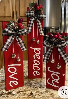 three red wooden signs decorated with christmas decorations and bows on top of a kitchen counter