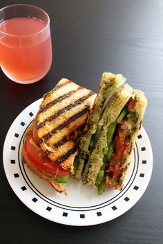 a grilled sandwich sitting on top of a white plate next to a glass of juice