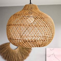 a rattan light hanging from a ceiling in a room with a painting on the wall