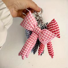 a person is holding onto a red and white bow keychain