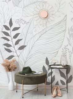 a chair and table in front of a wall with leaves on it