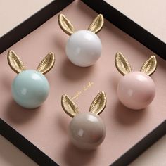 three different colored eggs in a box with gold leaves on the top and one is white