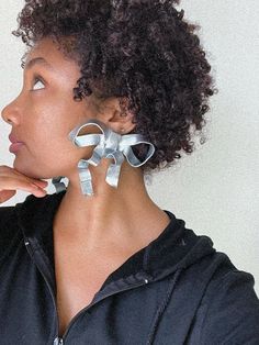 a woman with an earring made out of silver ribbon is looking off to the side