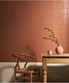 a wooden chair sitting next to a table with a vase on it