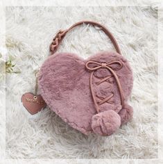 a pink heart shaped purse on top of a white rug