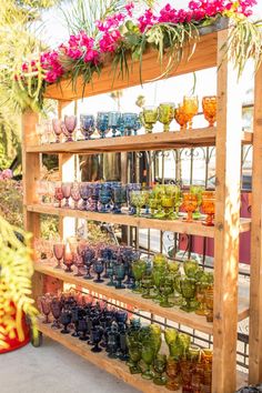 a display case filled with lots of colorful vases and flowers on top of wooden shelves