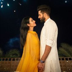 two people standing next to each other with fireworks in the background