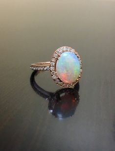 DeKara Designs Collection Our latest design!  An elegant and lustrous Opal cabochon surrounded by beautiful diamonds in a halo setting.Metal- 18K Rose Gold, .750.**** This Specific Ring Is a Size 6 3/4 ****Stones- Center Features a Oval Fiery Opal Cabochon Cut 2.00 Carats, 11.10 MM Long, 9 MM Wide, 44 Round Diamonds, I Color SI1 Clarity, 0.35 Carats.Latest of my creations.  A beautiful Opal Halo Diamond Ring.  The Opal is professionally prong set in between 4 double prongs.  There are 10 pave se Luxury Rose Gold Opal Gemstone Ring, Anniversary Diamond Cabochon Ring, Luxury Rose Gold Cabochon Rings, Formal Rose Gold Cabochon Ring, Luxury Opal Ring With Diamond Halo, Luxury Diamond Halo Opal Ring, Luxury Diamond Opal Ring With Halo, Luxury Opal Diamond Ring With Halo, Diamond Opal Cabochon Ring For Anniversary