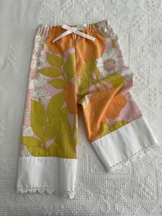 a pair of shorts with flowers on them sitting on a white bed sheet and lace