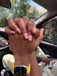 a woman holding her hand up in the back seat of a car while wearing a yellow watch