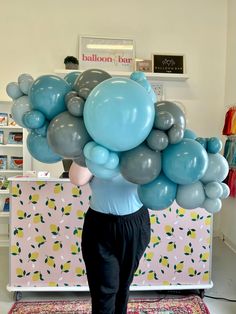 a woman is holding up balloons in the shape of a cloud on top of her head