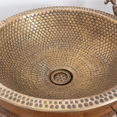 a round metal sink sitting on top of a wooden counter next to a faucet