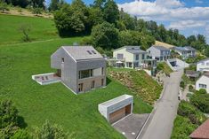 an aerial view of some houses on a hill in the middle of a green field