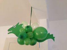 a green dragon balloon hanging from the ceiling with balloons attached to it's back