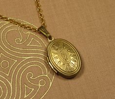 This pretty medallion pendant features a stylized sun on the front. The medallion is attached to a delicate pea chain that closes securely with a snap hook. The medallion can be opened from the side so that there is space inside for small memories that can always accompany you. -- Dimensions -- Length of chain 50 cm Medallion 24 x 14 mm -- MATERIAL -- The medallion chain is made of pure brass, an alloy of copper and zinc. Over time, the warm gold tone will acquire a patina that gives the piece o Gold Medallion Locket Necklace With Lobster Clasp, Brass Medallion Locket Necklace With Adjustable Chain, Gold Medallion Locket Necklace In Brass, Adjustable Gold Locket Necklace Nickel Free, Nickel-free Gold Metal Locket Necklace, Gold Metal Locket Necklace Nickel Free, Gold Oval Pendant Locket Necklace, Nickel Free, Gold Adjustable Locket Necklace With Vintage Charm, Gold Brass Amulet Locket Necklace