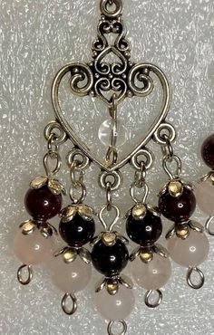 Passion Statement. Garnet and Rose Quartz beads dangling from a heart shaped filigree with a small Quartz Crystal bead hanging in the middle of the heart. Whether it's date night with that special someone, or just some self-love to remind yourself that you are so worth it. Either way, these amazing beauties are sure to make you feel so loved.Earrings hang about 3" from surgical stainless steel ear wires.Any metals used in jewelry are all nickel free, tarnish resistant (except for copper, which w Elegant Heart-shaped Jewelry With Dangling Beads, Valentine's Day Jewelry With Dangling Beads As Gift, Valentine's Day Dangling Beads Jewelry Gift, Valentine's Day Jewelry With Dangling Beads, Valentine's Day Jewelry Gift With Dangling Beads, Valentine's Day Gift Jewelry With Dangling Beads, Elegant Heart Beaded Dangle Earrings, Elegant Heart-shaped Earrings With Dangling Beads, Bohemian Heart Beads Earrings For Valentine's Day