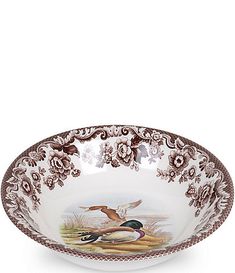 a brown and white bowl with two birds on the bottom, sitting in front of a white background