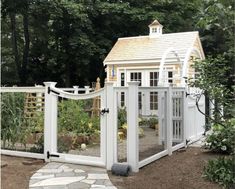 a small white chicken coop in the middle of a garden